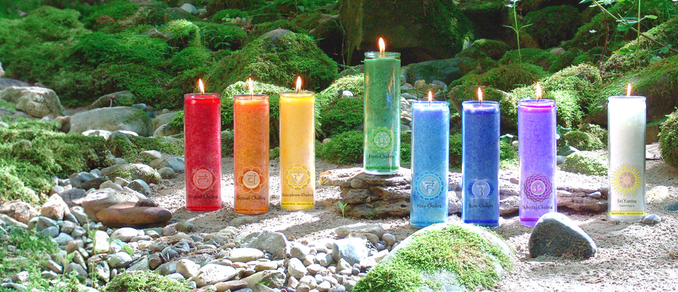 Farbige Stearin Kerzen mit Chakra Symbolen in näturlicher Landschaft